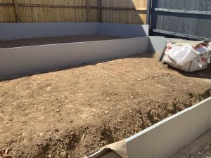 Three-tier sloping garden with paving, artificial grass and white cobbles, Stone