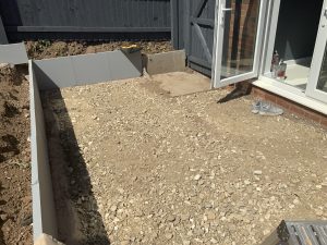Three-tier sloping garden with paving, artificial grass and white cobbles, Stone
