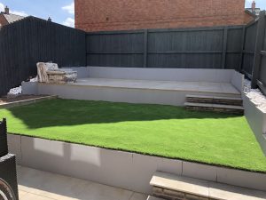 Three-tier sloping garden with paving, artificial grass and white cobbles, Stone