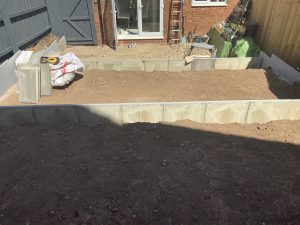 Three-tier sloping garden with paving, artificial grass and white cobbles, Stone
