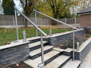 50m² porcelain patio with split-face granite wall, sleeper planters and lighting, Stone
