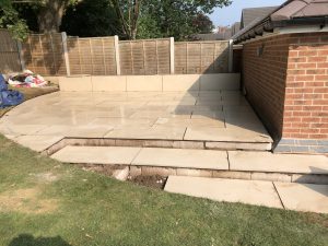 50m² porcelain patio with split-face granite wall, sleeper planters and lighting, Stone