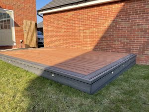 Composite decking with contrasting picture-frame border, deck lights and 7m oak sleeper planter