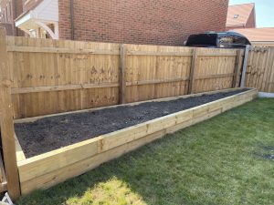 Composite decking with contrasting picture-frame border, deck lights and 7m oak sleeper planter
