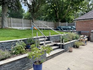 50m² porcelain patio with split-face granite wall, sleeper planters and lighting, Stone