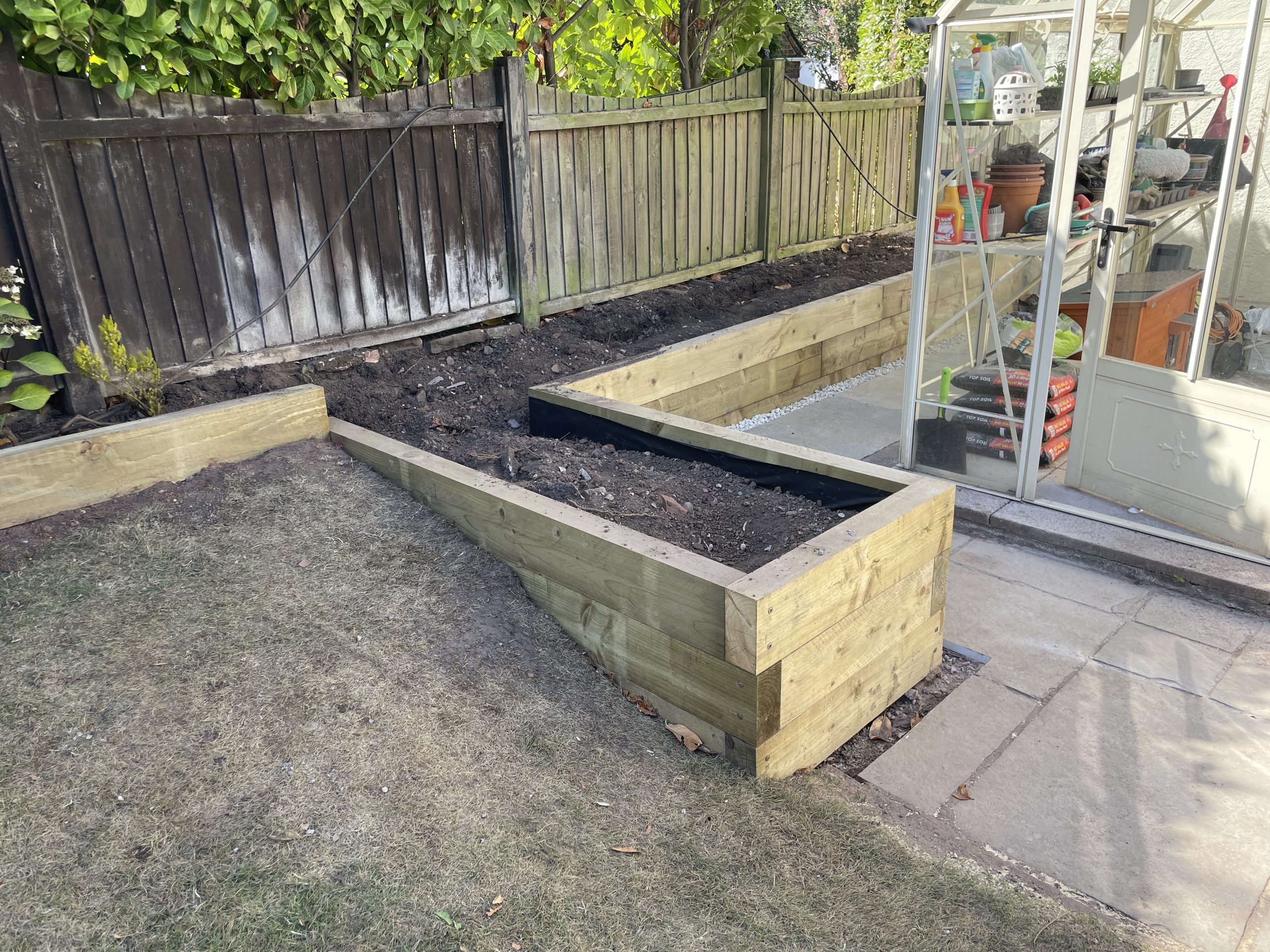 Green treated timber sleeper bed and retaining wall around a greenhouse, Trentham
