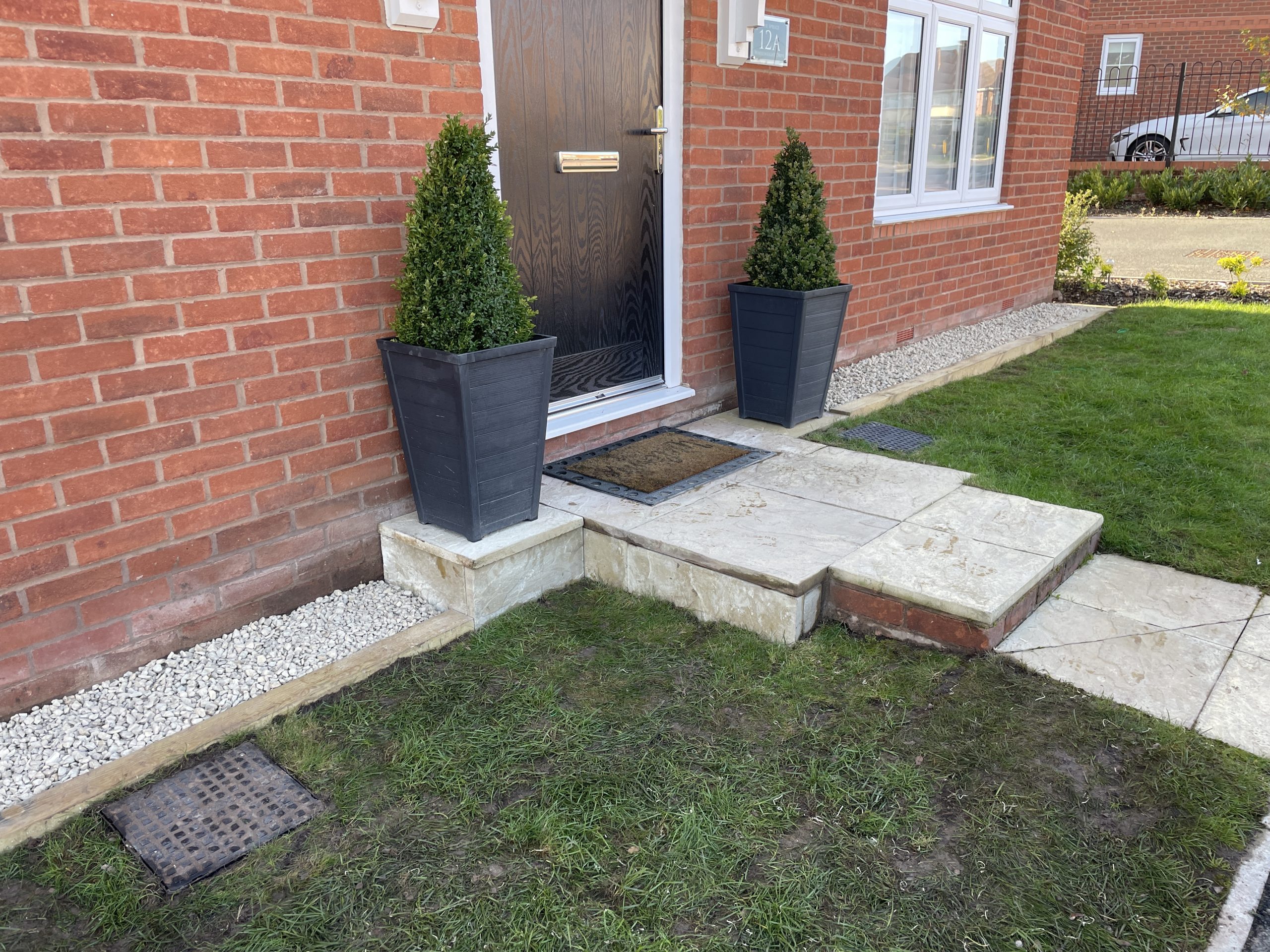 Front entrance framed by low sleeper borders and white stone, Stone