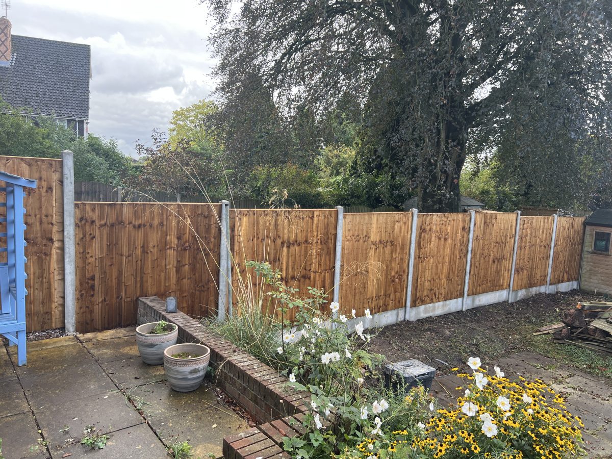 Brown featheredge closeboard fence on concrete posts and gravel boards, Stone